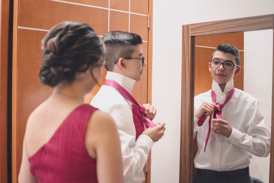Ženin popravlja kravato pred ogledalom